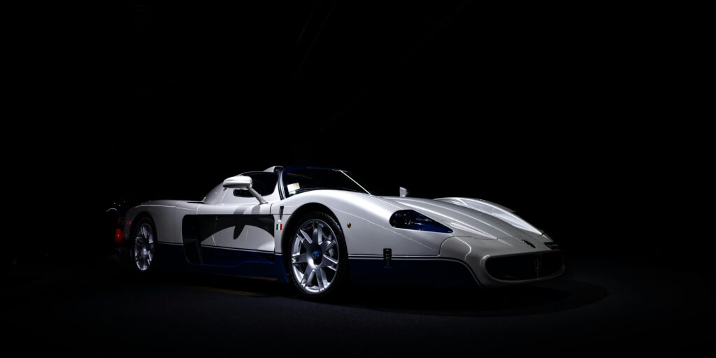 A stylish white sports car highlighted against a dark background, emphasizing luxury and speed.